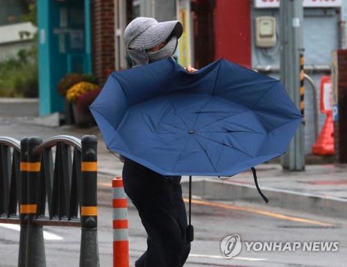 La foto, tomada el 19 de septiembre de 2022, muestra a una mujer sosteniendo su paraguas frente a los fuertes vientos provocados por el tifón Nanmadol, cerca de un puerto en la ciudad portuaria de Busan, en el sudeste de Corea del Sur, antes de que el poderoso tifón Nanmadol, el 14º de este año, llegara, ese mismo día por la tarde, a la parte suroriental del país.