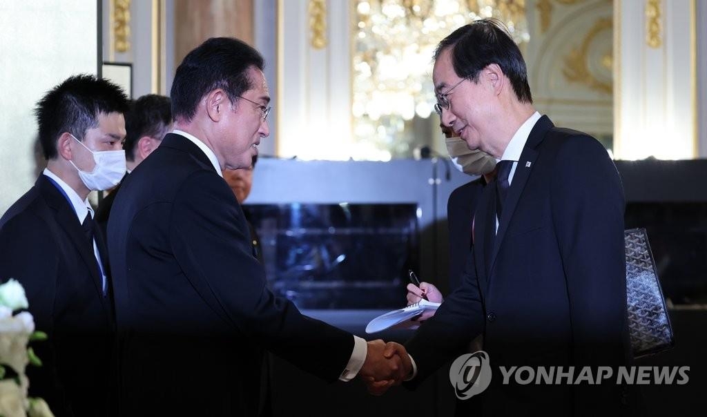 El primer ministro de Corea del Sur, Han Duck-soo (dcha.), estrecha la mano del primer ministro de Japón, Fumio Kishida, el 27 de septiembre de 2022, antes de una recepción en la Casa para Visitas de Estado, en Tokio, tras el funeral de Estado por Shinzo Abe, antecesor de Kishida.