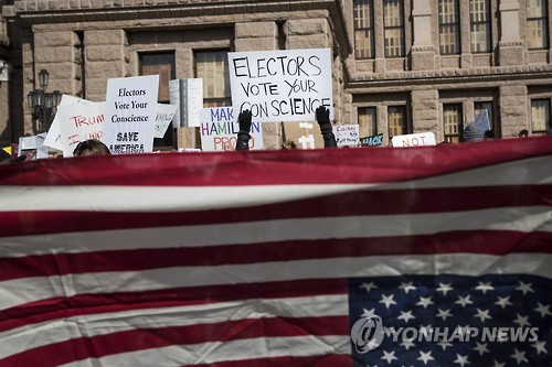 19일(현지시간) 미국 텍사스 주 오스틴 주 의사당 건물 앞에서 공화당 투표인단에게 '반란표'를 촉구하는 시민들[AP=연합뉴스]