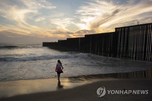 멕시코 티후아나 해변에 설치된 미국 국경장벽 앞에 서 있는 이민자 소녀 [AP=연합뉴스 자료 사진] 