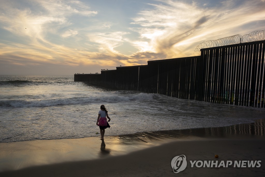 멕시코 티후아나 해변에 설치된 미국 국경장벽 앞에 서 있는 이민자 소녀 [AP=연합뉴스 자료 사진] 