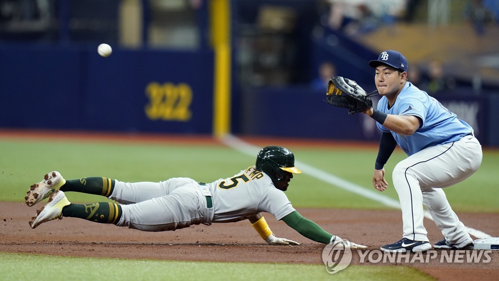 In this Associated Press photo, Tampa Bay Rays' first baseman Choi Ji-man (R) prepares to catch a pickoff throw by starter Tommy Romero as Tony Kemp of the Oakland Athletics dives back to the bag during the top of the first inning of a Major League Baseball regular season game at Tropicana Field in St. Petersburg, Florida, on April 12, 2022. (Yonhap)