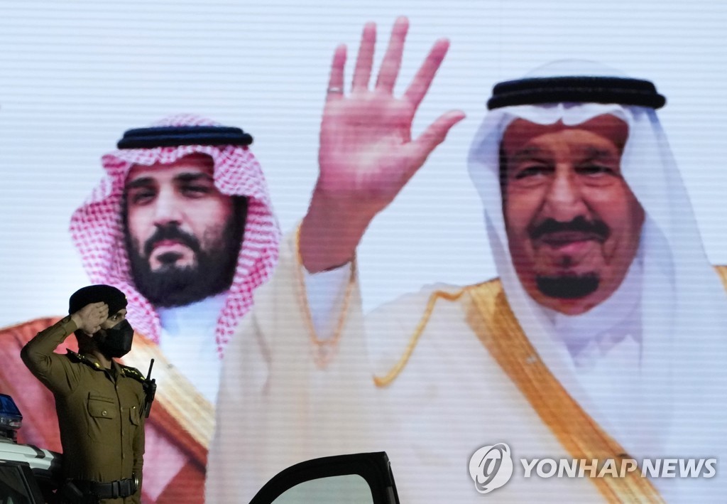 사우디 국왕과 왕세자의 영상 이미지에 경례하는 현지 경찰관