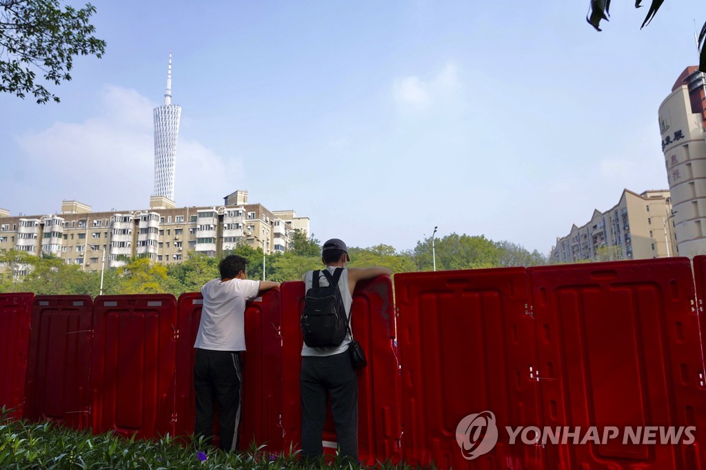 (AP=연합뉴스) 지난 11일 중국 광둥성 광저우 주민들이 바리케이트 너머로 봉쇄된 하이주구를 바라보는 모습. 2022.11.13. 