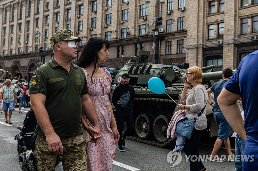 20일 우크라이나 군복을 입은 남성과 그의 손을 잡은 여성이 무기 전시를 바라보고 있다.