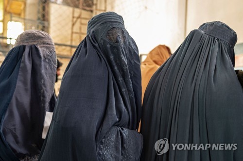 얼굴까지 모두 가리는 의상을 착용하고 국제구호단체가 제공하는 구호식량을 받기 위해 줄을 서고 있는 아프간 여성들
