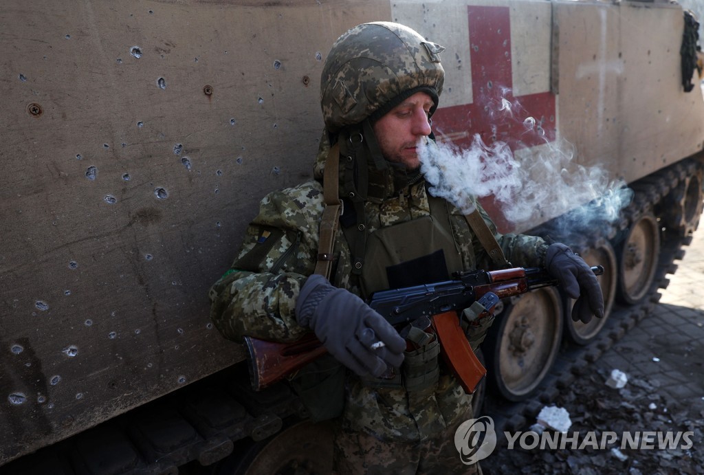 우크라이나 군인이 장갑차에 기대 휴식을 취하고 있다.