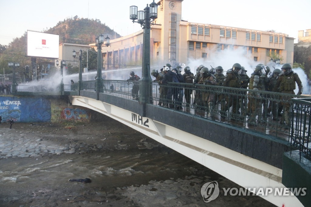지난 2일(현지시간) 칠레 산티아고에서 경찰들이 다리 아래로 떨어진 소년을 지켜보고 있다.