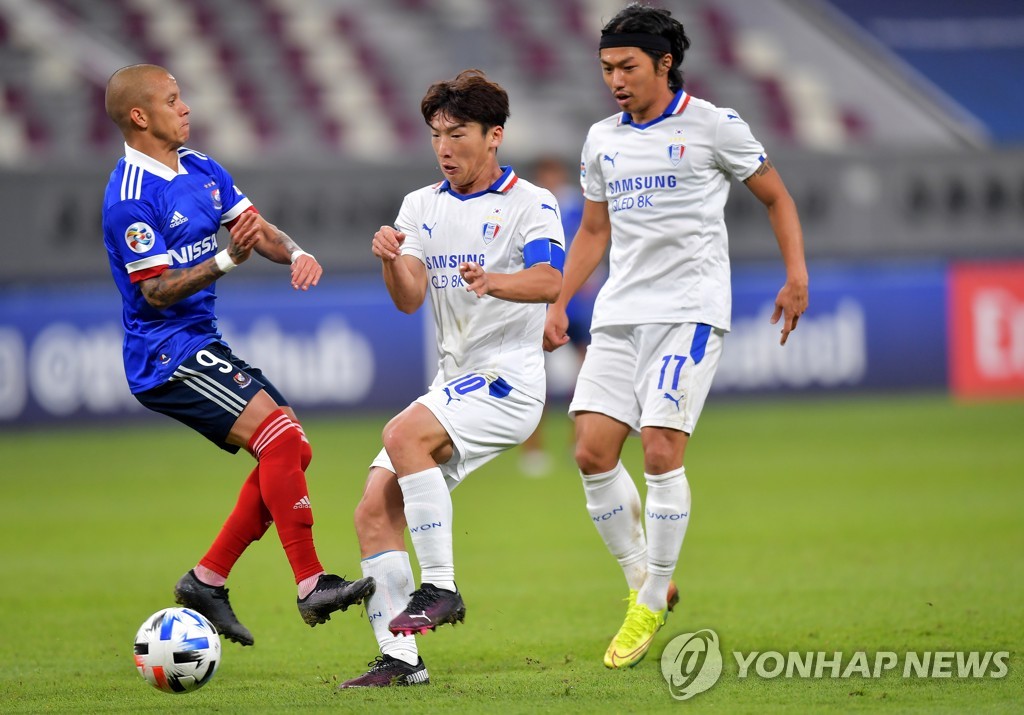In this EPA photo, Kim Min-woo (C) and Ko Seung-beom (R) of Suwon Samsung Bluewings are in action against Marcos Junior of Yokohama F. Marinos during the teams' round of 16 match at the Asian Football Confederation Champions League at Khalifa International Stadium in Doha on Dec. 7, 2020. (Yonhap)