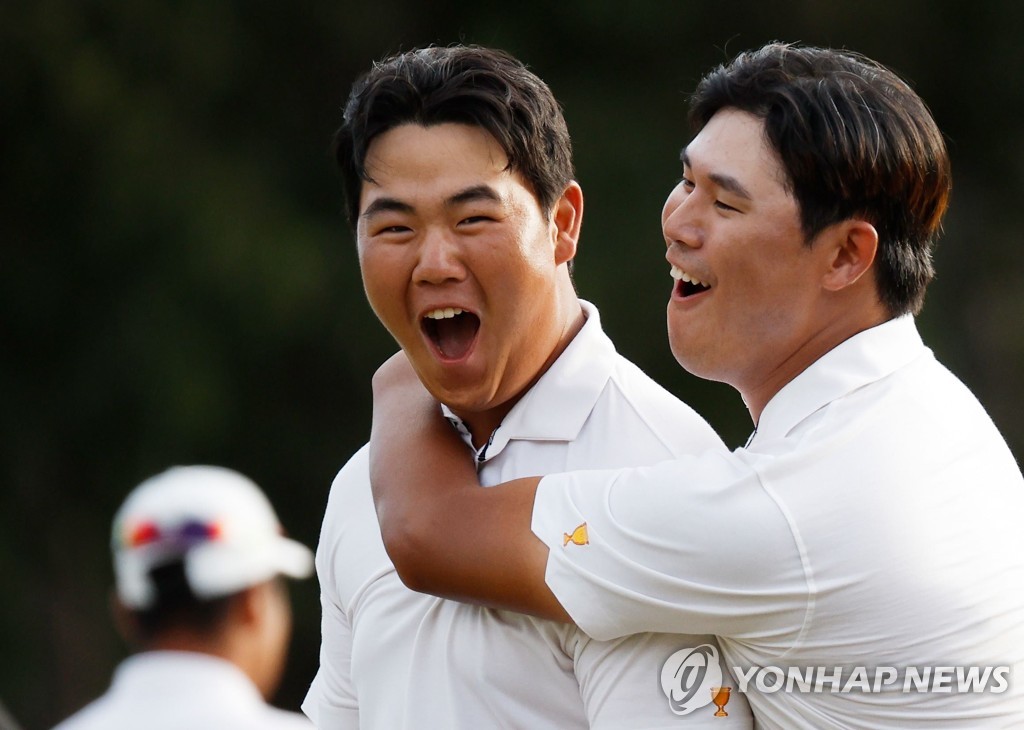 In this Getty Images photo, South Korean Kim Joo-hyung (L) is congratulated by his International teammate Kim Si-woo after making a birdie putt at the 18th hole to beat Patrick Cantlay and Xander Schauffele of the United States in their fourball match at the Presidents Cup at Quail Hollow Club in Charlotte, North Carolina, on Sept. 24, 2022. (Yonhap)