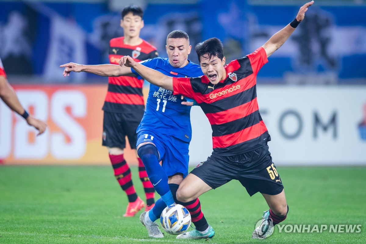 In this Xinhua photo, Choi Hyun-Woung (R) of Pohang Steelers battles Davidson Pereira of Wuhan Three Towns FC for the ball during the clubs' Group J match at the Asian Football Confederation Champions League at Wuhan Sports Center Stadium in Wuhan, China, on Dec. 6, 2023. (Yonhap)