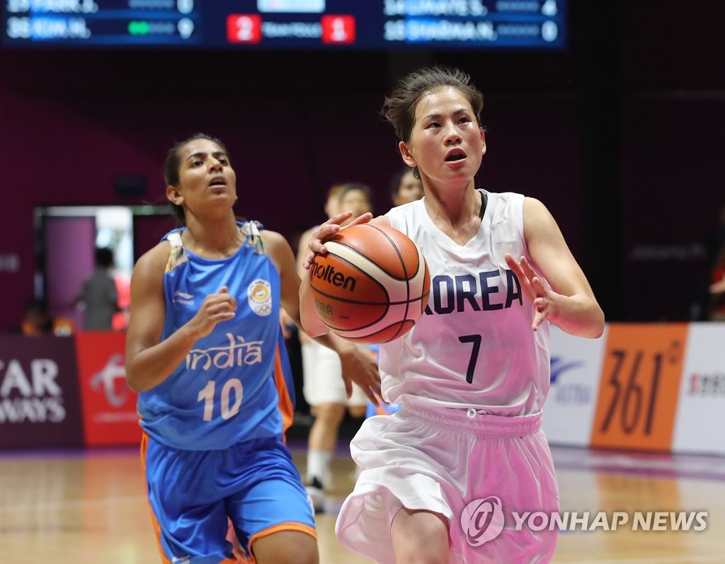 In this file photo from Aug. 20, 2018, North Korean guard Jang Mi-gyong (R) of the unified Korean women's basketball team drives to the basket past Madhu Kumari of India during the teams' Group X match at the 18th Asian Games at GBK Basketball Hall in Jakarta. (Yonhap)
