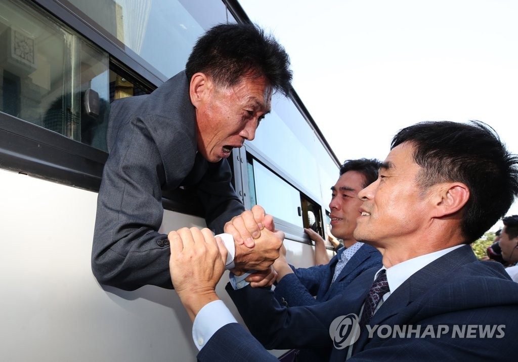 In the Unification Ministry pooled photo, taken Aug. 26, 2018, a North Korean man (on bus) is seen tightly grabbing the hand of his South Korean relative who was set to head back to South Korea at the end of a family reunion for separated families held in North Korea's Mount Kumgang. (Yonhap)