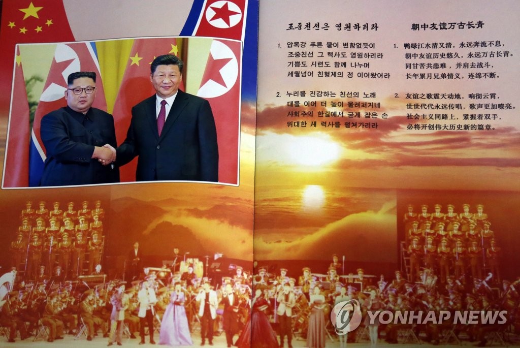 北朝鮮の金正恩・国務委員長（朝鮮労働党委員長）と中国の習近平国家主席が握手する姿が掲載されている公演のパンフレット＝（聯合ニュース）
