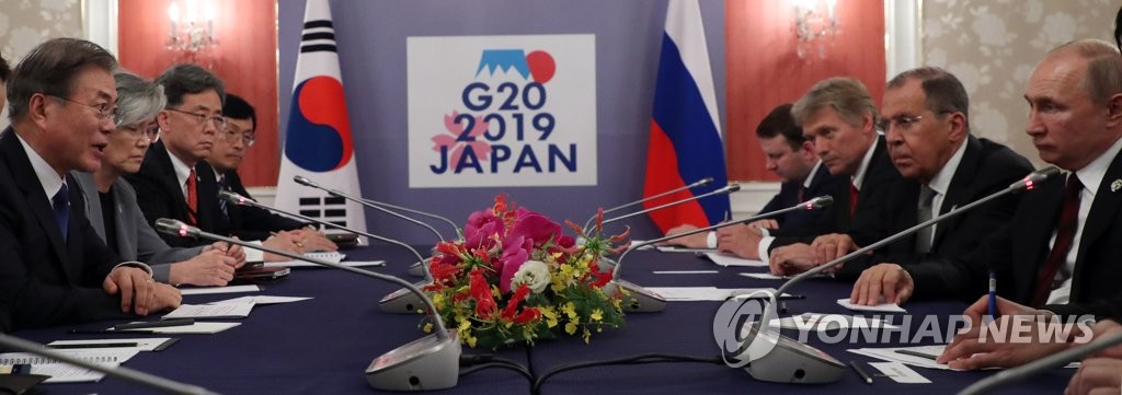 South Korean President Moon Jae-in (L) talks with Russian President Vladimir Putin (R) in their meeting at an Osaka hotel on June 29, 2019. (Yonhap)