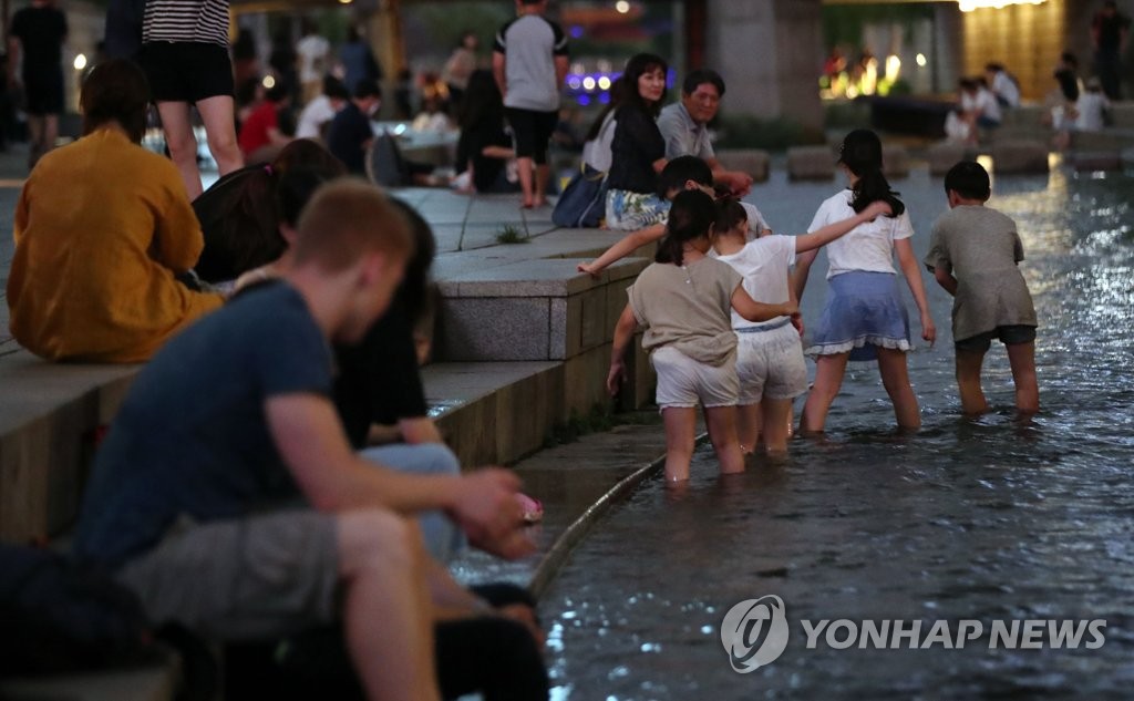 Des personnes cherchent un peu de fraîcheur au bord de la rivière Cheonggye, à Séoul. (Photo d'archives Yonhap)