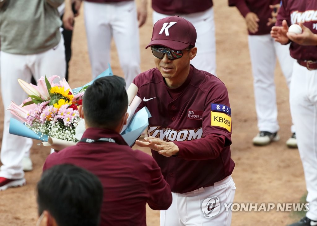 This file photo from May 5, 2020, shows Kiwoom Heroes' manager Son Hyuk (R) receiving a bouquet of flowers from his general manager Kim Chi-hyun after recording his first win as a Korea Baseball Organization manager against the Kia Tigers at Gwangju-Kia Champions Field in Gwangju, 330 kilometers south of Seoul. (Yonhap)