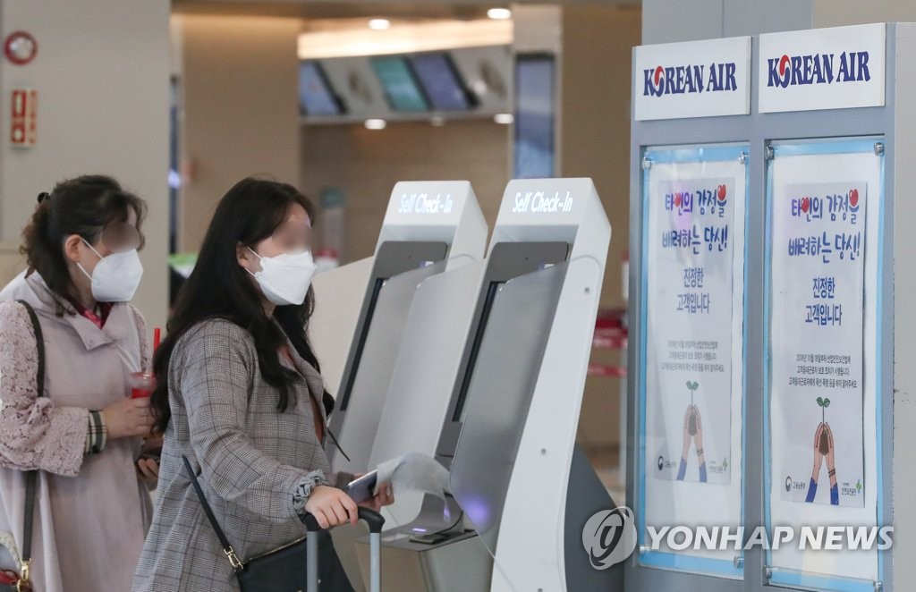 Travelers wearing protective masks check in at Gimpo International Airport in western Seoul on May 17, 2020. (Yonhap)