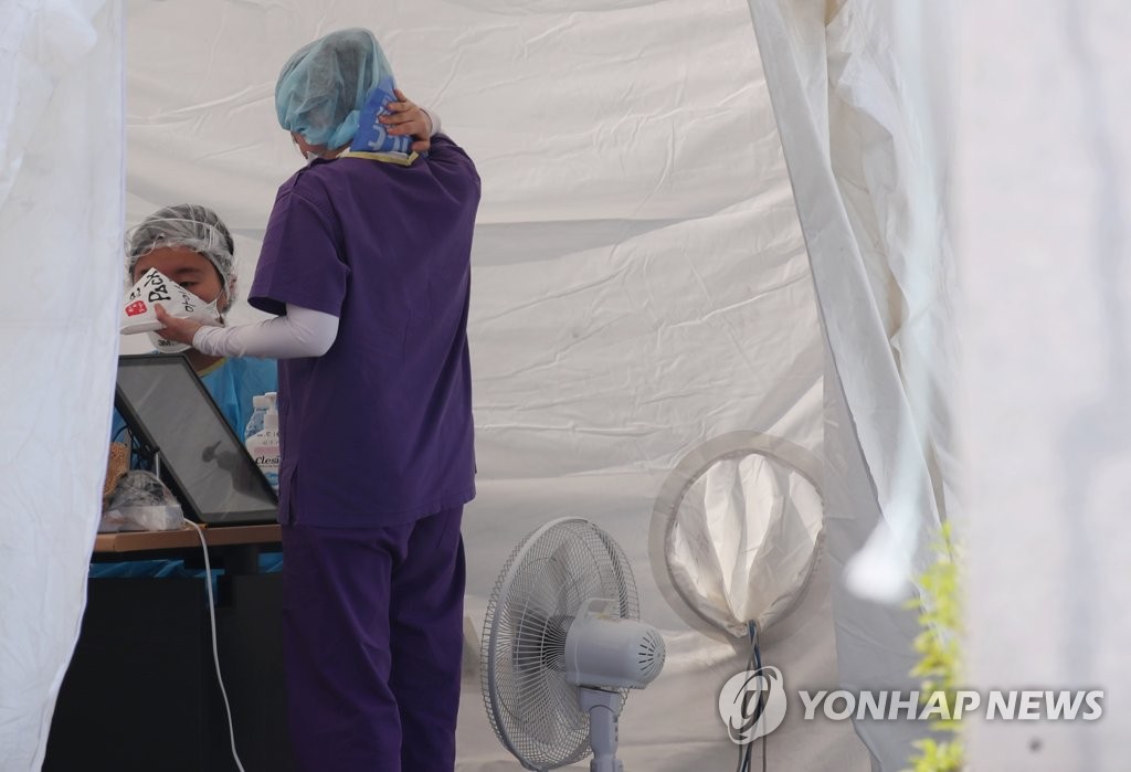 Health workers at a screening center in the eastern Seoul ward of Jungnang use ice packs to cool down on June 8, 2020. (Yonhap)