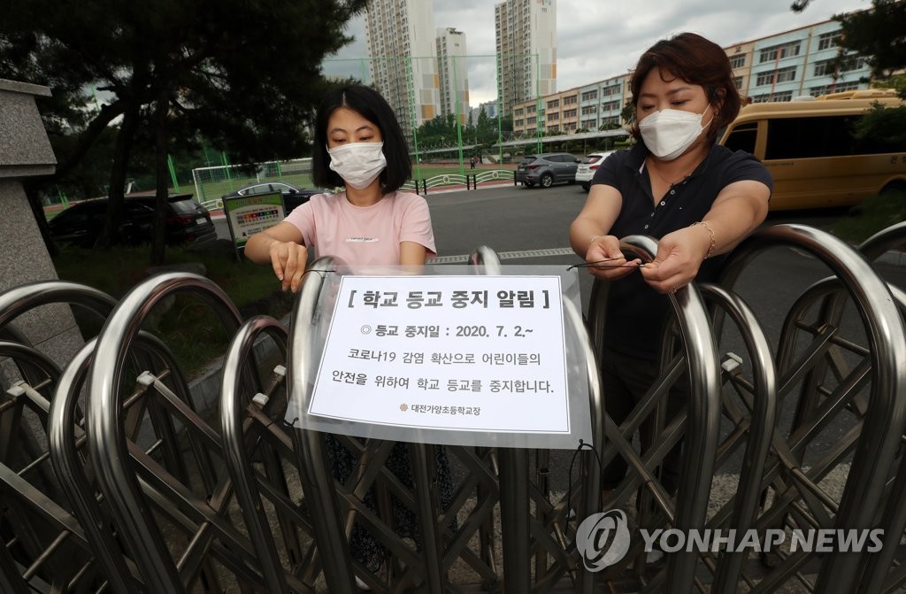School officials at an elementary school in Daejeon, around 160 kilometers south of Seoul, install a sign on class suspension at the school entrance after the local education office advised schools in the area to close in a precautionary measure on July 1, 2020. (Yonhap)