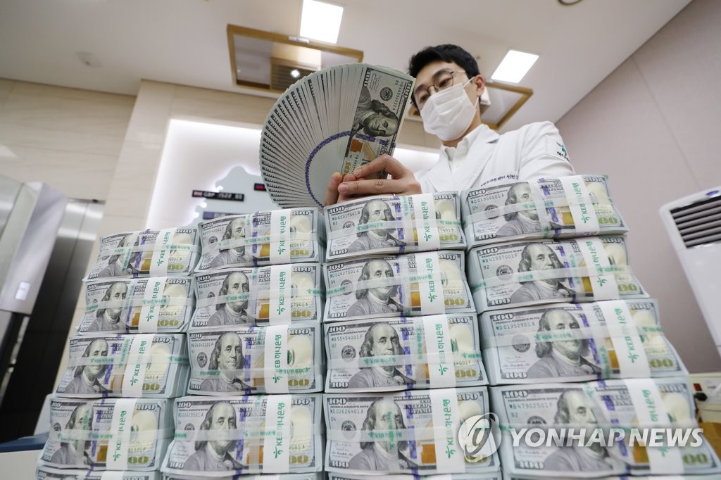 In the photo, taken July 3, 2020, a bank official is seen inspecting U.S. dollars before their release at a Seoul branch of Hana Bank. (Yonhap)