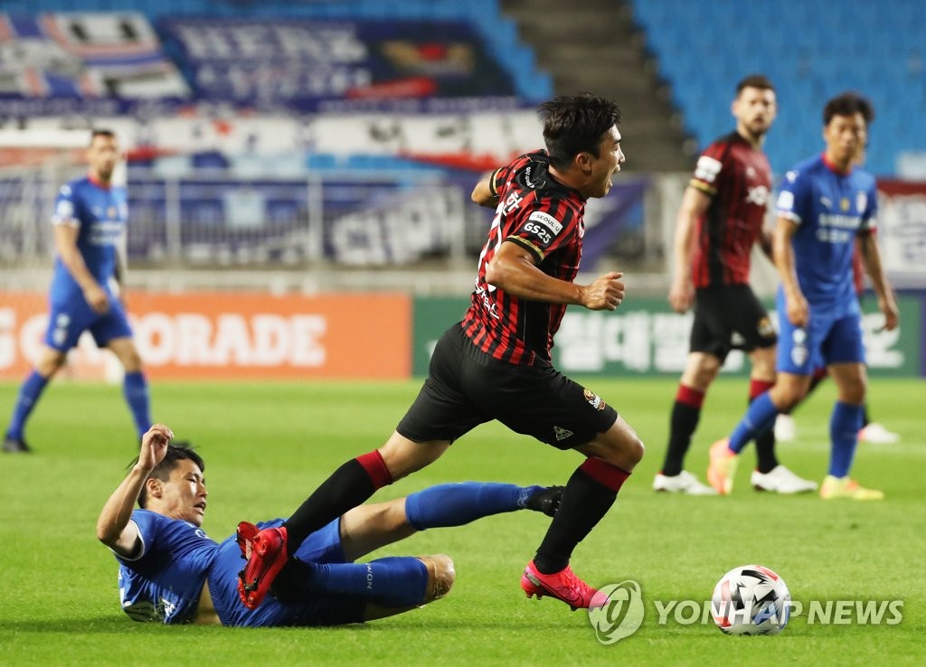 In this file photo from July 4, 2020, Go Yo-han of FC Seoul (R) is tackled by a Suwon Samsung Bluewings player during their K League 1 match at Suwon World Cup Stadium in Suwon, 45 kilometers south of Seoul. (Yonhap)
