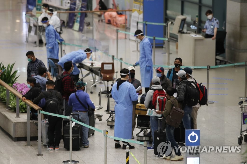 Medical workers provide instructions to foreign arrivals at Incheon International Airport, west of Seoul, on July 23, 2020. (Yonhap)