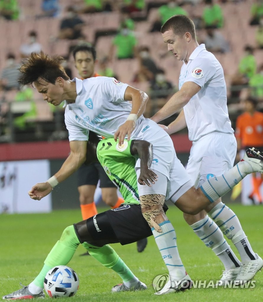 In this file photo from Aug. 1, 2020, Mo Barrow of Jeonbuk Hyundai Motors (L) is tangled up with Kim Kwang-suk of Pohang Steelers (C) during a K League 1 match at Jeonju World Cup Stadium in Jeonju, 240 kilometers south of Seoul. (Yonhap)