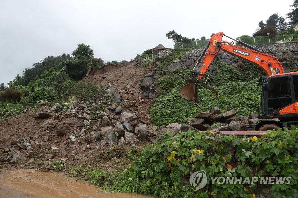 An official uses an excavator to restore a road covered by soil following a landside in Gapyeong, Gyeonggi Province, on Aug. 4, 2020. (Yonhap)