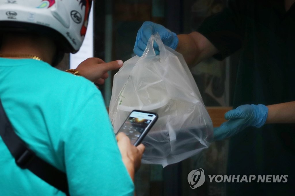 A deliveryman receives packaged meals from a restaurant in central Seoul on Sept. 10, 2020. (Yonhap)