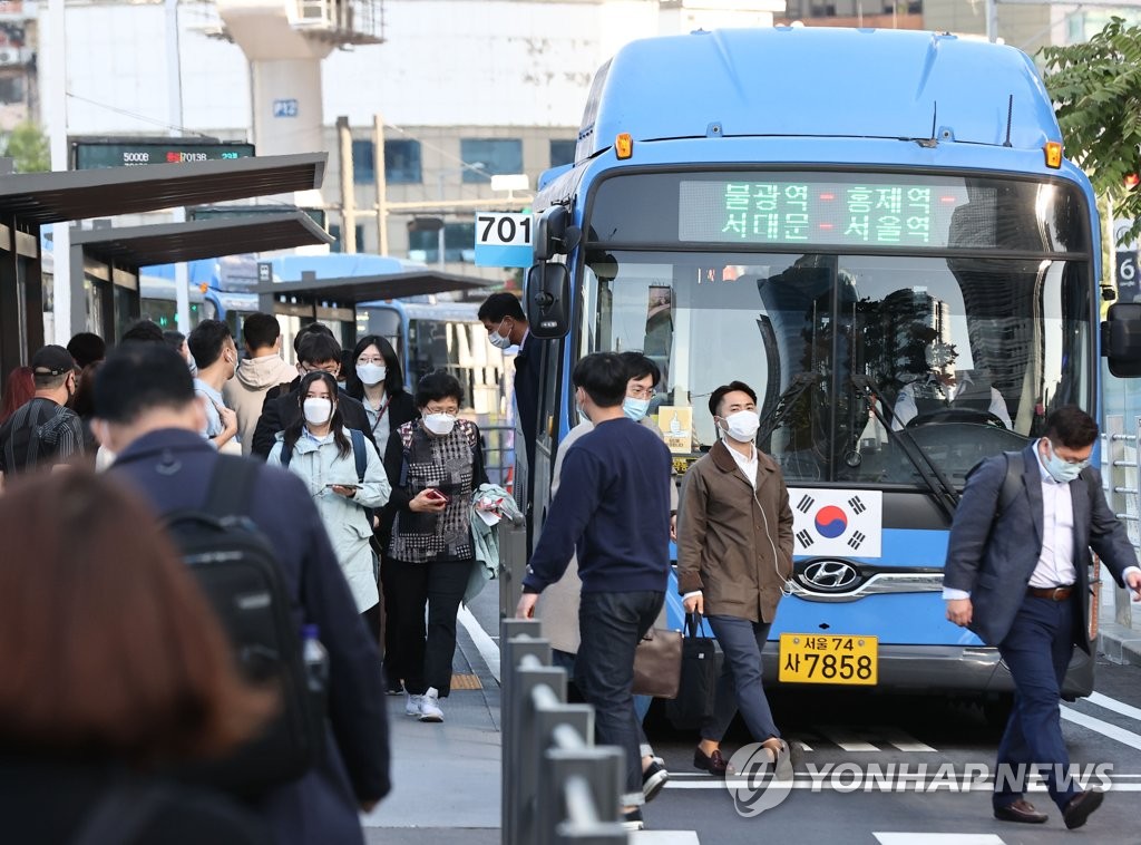 Commuters wearing protective masks wait for buses in central Seoul on Oct. 5, 2020. (Yonhap) 