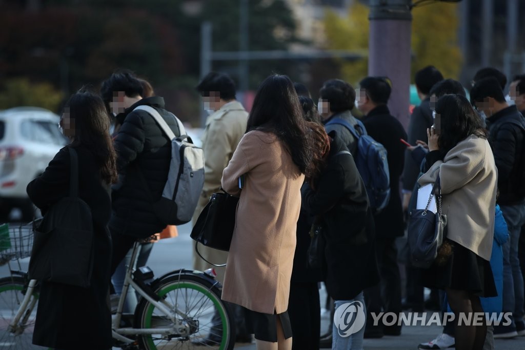 Commuters wearing protective masks stand at Gwangwhamun Square in central Seoul on Nov. 10, 2020. (Yonhap) 