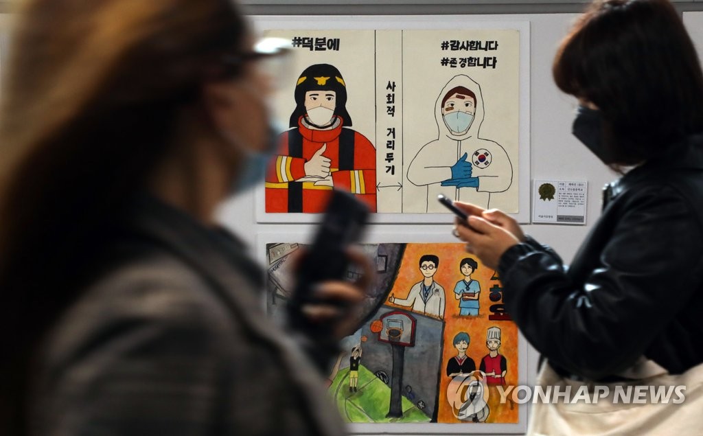 Citizens walk past posters on social distancing in a Seoul subway station on Nov. 17, 2020. (Yonhap)