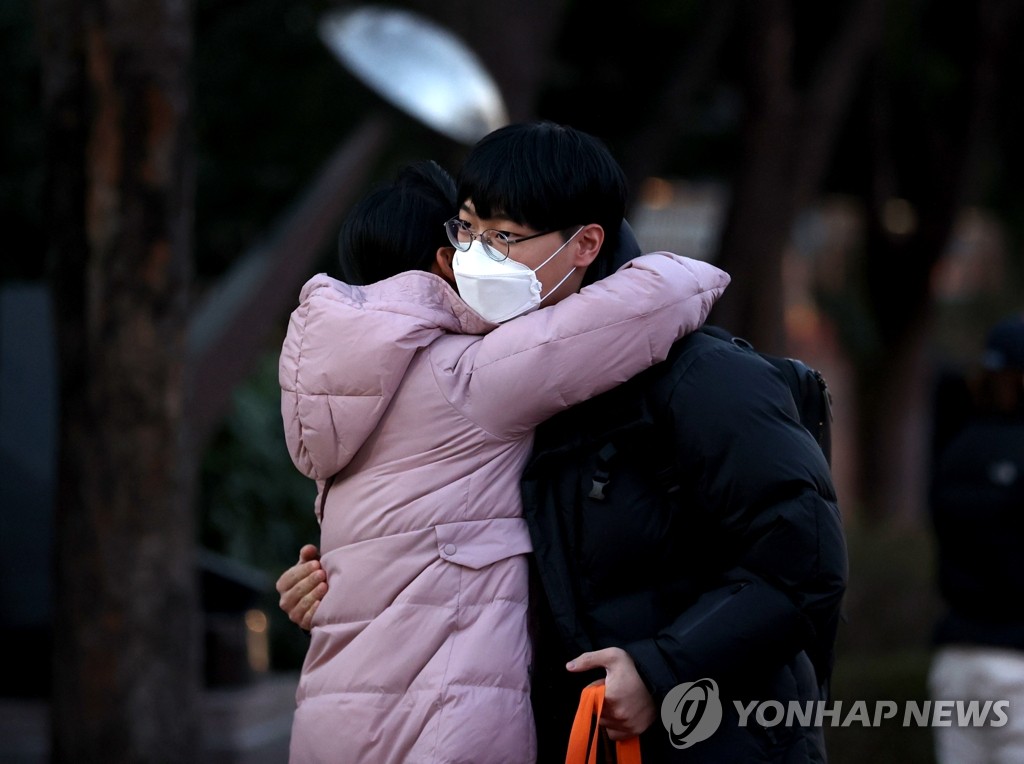 Une mère embrasse son fils devant le centre d'examen installé au lycée Dongsung dans le centre de Séoul, le jeudi 3 décembre 2020. 