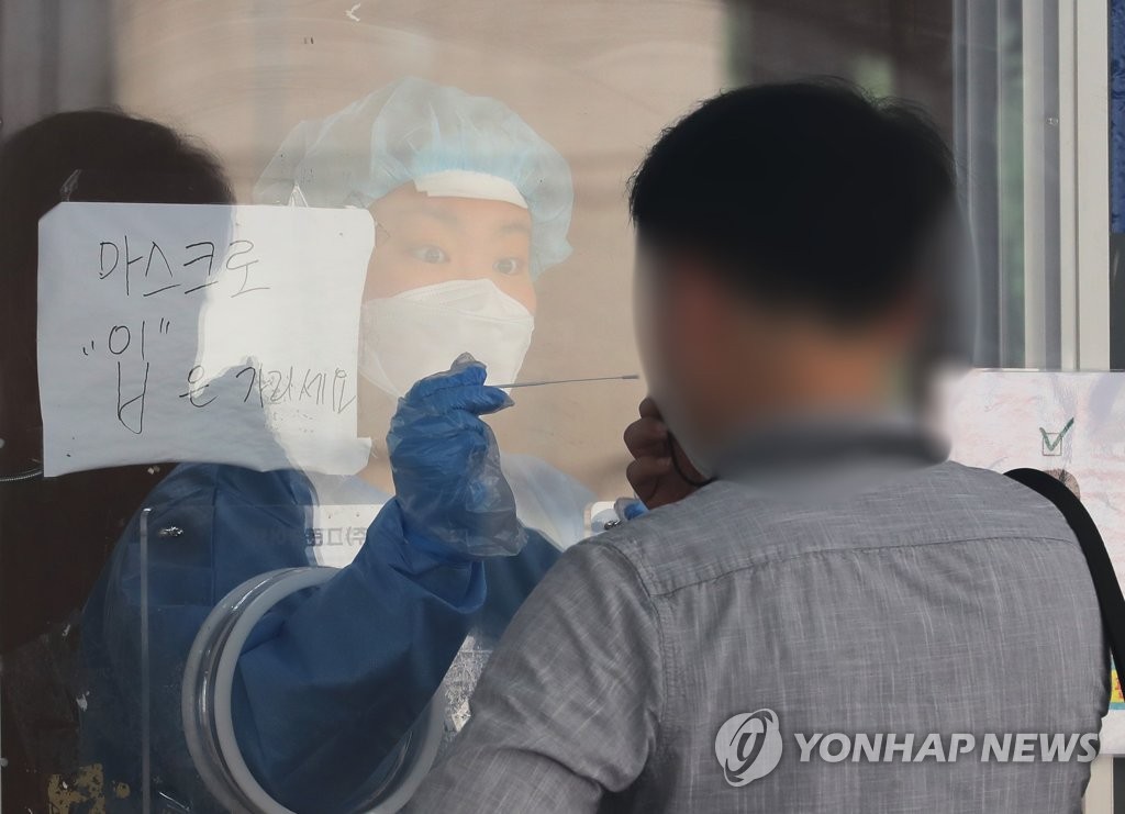 A health worker in a protective suit collects a sample from a citizen at a makeshift virus testing clinic in Seoul on June 8, 2021. (Yonhap)