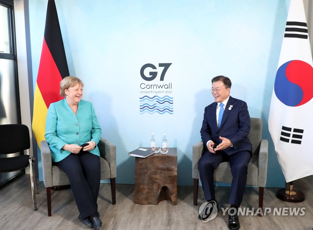 Le président Moon Jae-in (à dr.) s'entretient avec la chancelière allemande Angela Merkel en marge du sommet du G7 en Cornouailles, en Grande-Bretagne, le 12 juin 2021.