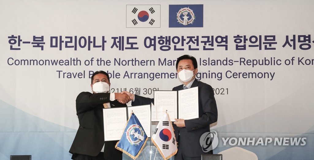 Le vice-ministre sud-coréen du Transport, Hwang Seong-kyu (à droite), serre la main du gouverneur de Saipan, Ralph Torres, après avoir signé un accord pour établir une «bulle de voyage» avec Saipan, à Séoul, le 30 juin 2021.