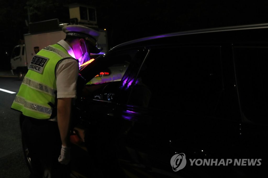 A police officer stops a car on an intersection near Seogang Bridge in Seoul on July 14, 2021, ahead of a planned drive-through rally by small business owners. (Yonhap)