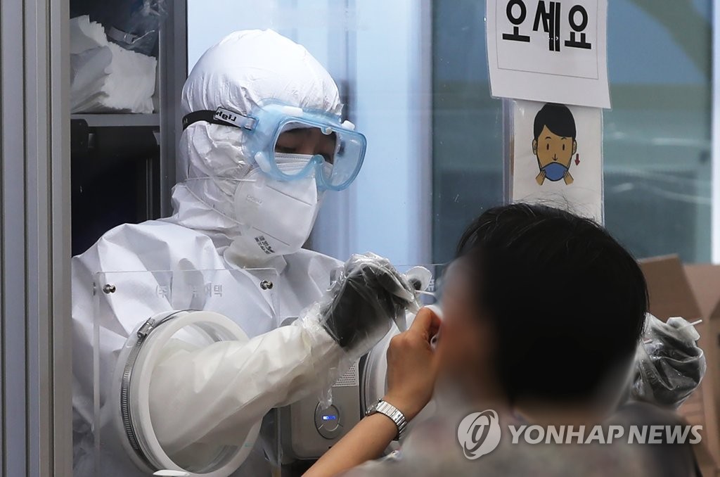 ソウル市松坡区の保健所に設置されている新型コロナウイルスの専用診療所で、市民が検体の採取を受けている＝２２日、ソウル（聯合ニュース）