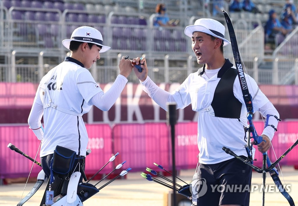 South Korean archers An San (L) and Kim Je-deok celebrate during the final of the mixed team event at the Tokyo Olympics at Yumenoshima Park Archery Field in Tokyo on July 24, 2021. (Yonhap)