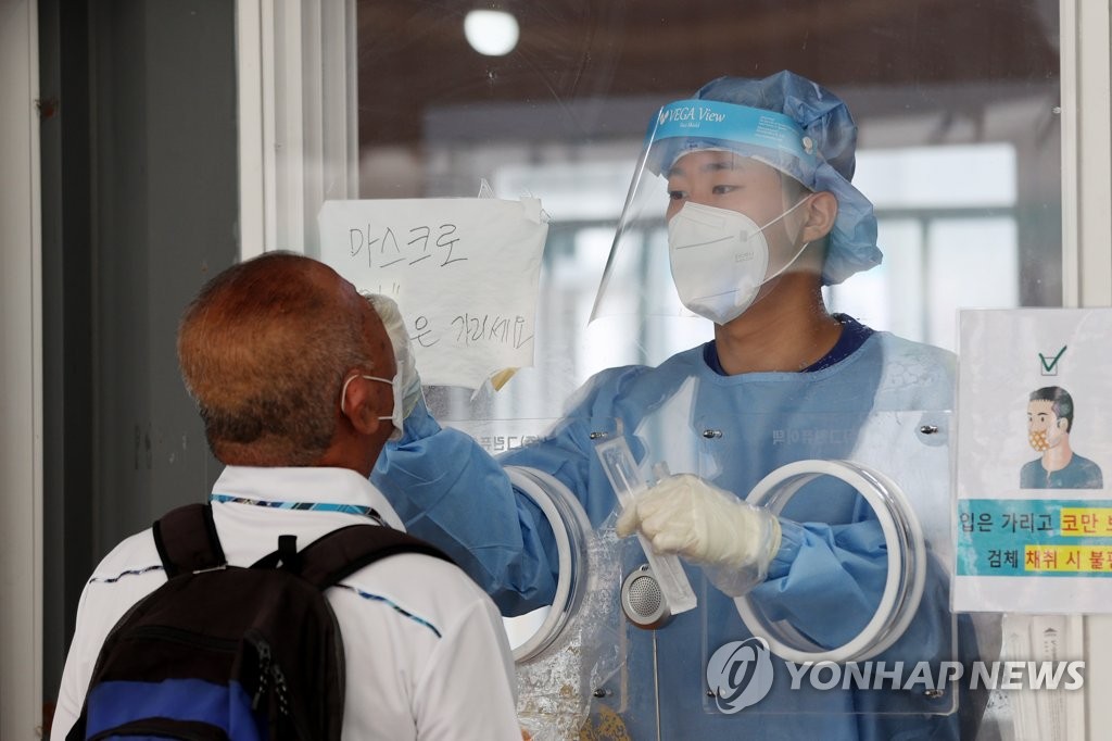 A medical worker conducts a COVID-19 test at a makeshift testing center near Seoul Station on Aug. 8, 2021. (Yonhap) 