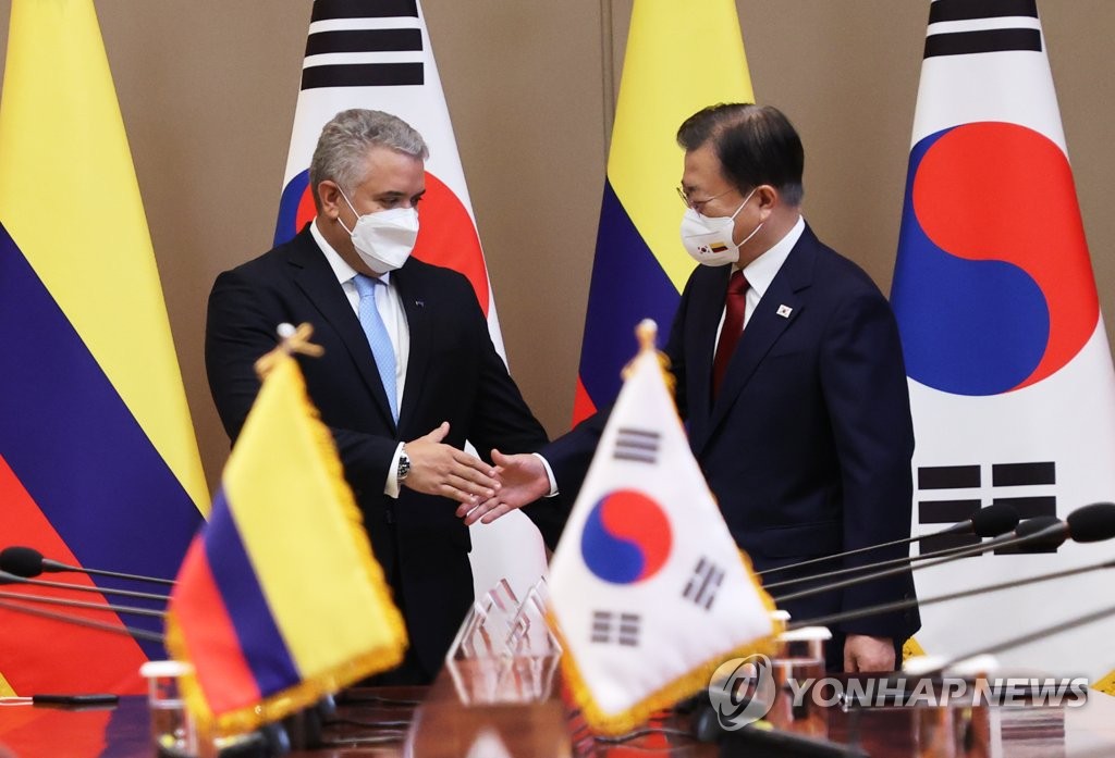 El presidente surcoreano, Moon Jae-in (dcha.), estrecha la mano del presidente colombiano, Iván Duque Márquez, durante una cumbre celebrada, el 25 de agosto de 2021, en la oficina presidencial, Cheong Wa Dae, en Seúl.