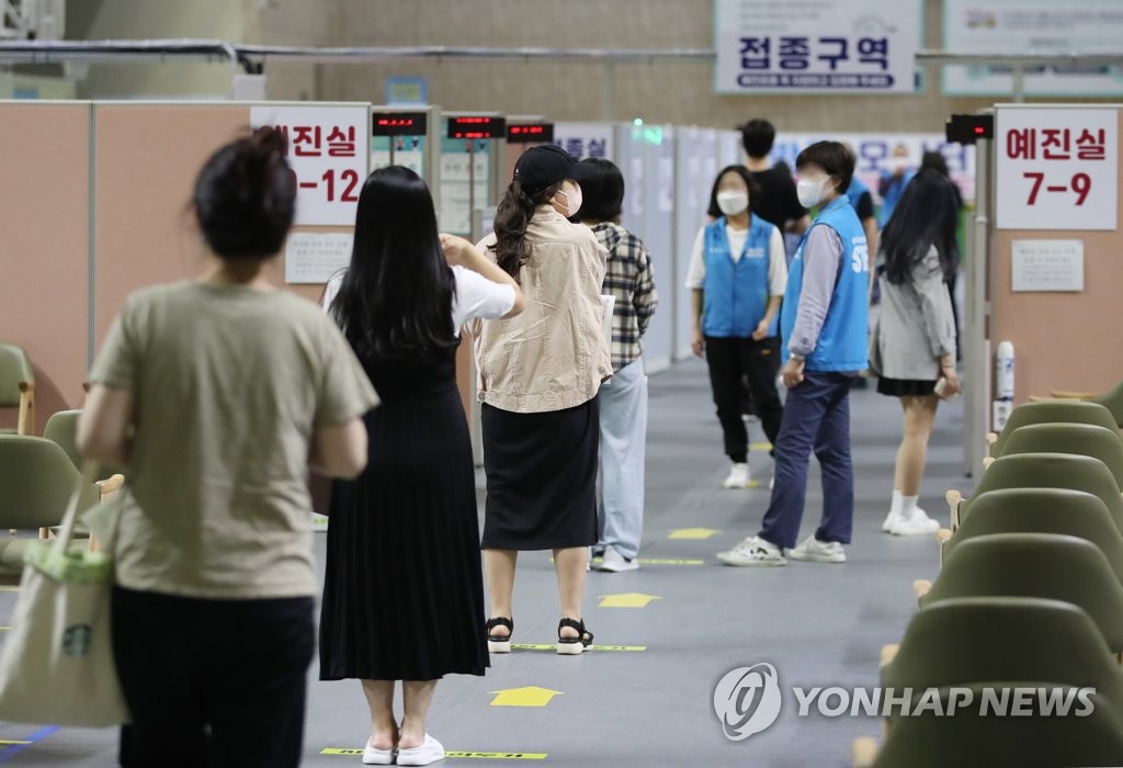 This photo taken on Oct. 5, 2021 shows people waiting to receive COVID-19 vaccines at a makeshift vaccination center in a gymnasium located in Dongjak, southern Seoul. (Yonhap)