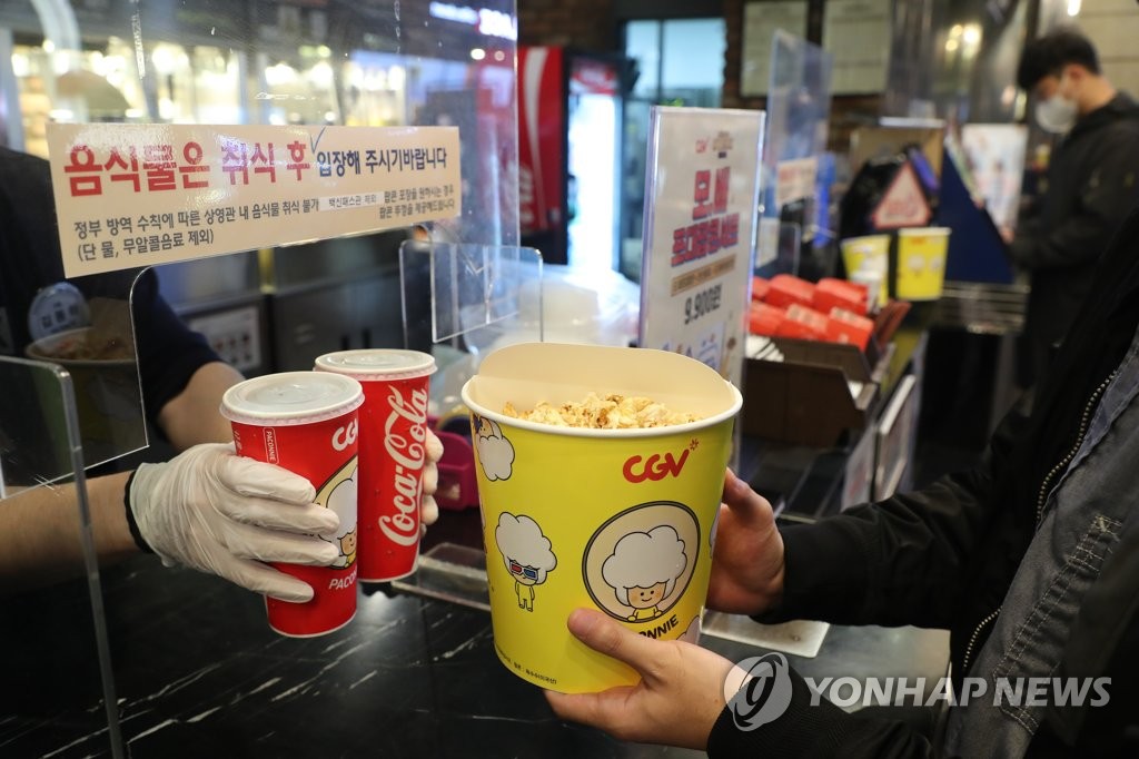 In this file photo taken Nov. 1, 2021, a moviegoer buys a bucket of popcorn and sodas at a theater in Seoul. (Yonhap)