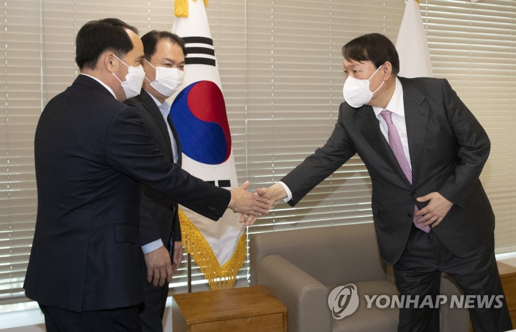 Yoon Seok-youl (R), the presidential candidate of the main opposition People Power Party, shakes hands with Choi Won-il (L), the retired captain of the sunken naval ship Cheonan, at his party's headquarters in Seoul on Nov. 17, 2021. (Pool photo) (Yonhap)