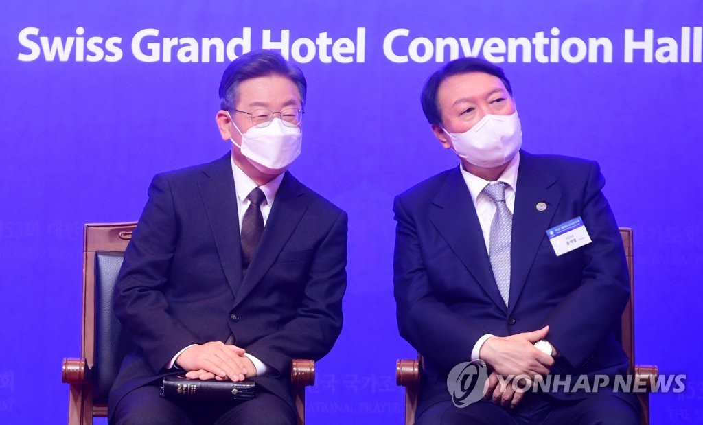 Lee Jae-myung (L), the presidential nominee of the ruling Democratic Party, and Yoon Suk-yeol, the nominee of the main opposition People Power Party, attend the Korea National Prayer Breakfast at a Seoul hotel on Dec. 2, 2021. (Pool photo) (Yonhap)
