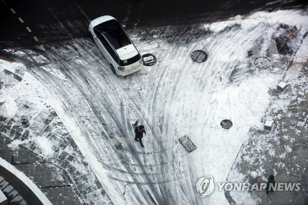 지난달 19일 오전 시민들이 전날 내린 눈이 쌓여있는 서울 종로구의 한 이면도로를 지나고 있다. [연합뉴스 자료사진]