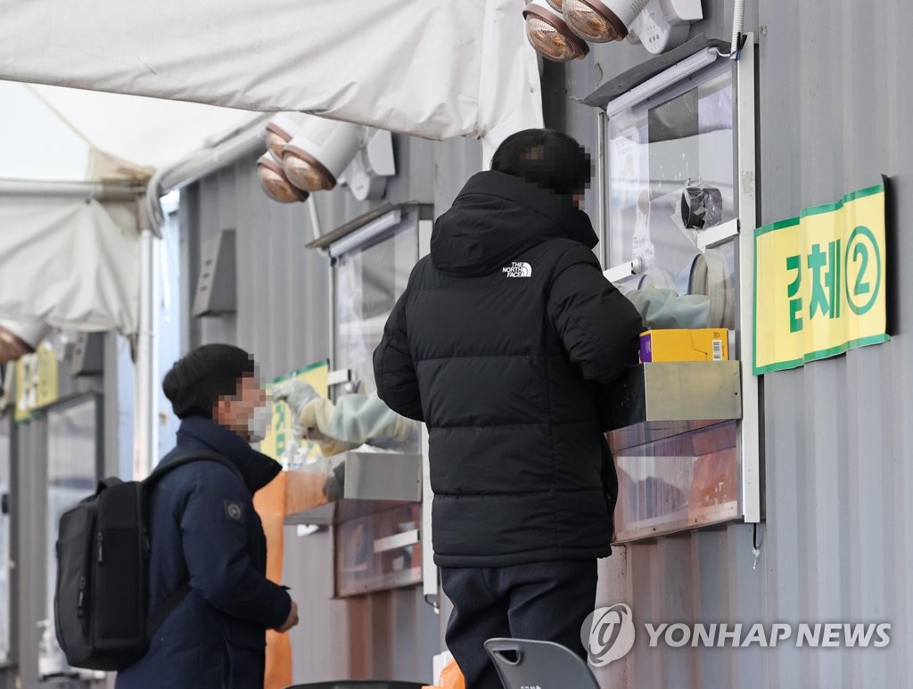 De personnes subissent un test de dépistage pour le nouveau coronavirus (Covid-19) dans un centre devant la mairie de Séoul, le vendredi 7 janvier 2022. 