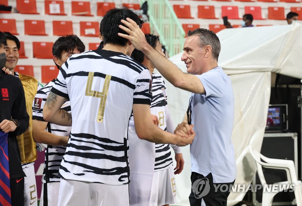 South Korea head coach Paulo Bento (R) celebrates with his defensive back Kim Min-jae after the team clinched a spot for the 2022 FIFA World Cup with a 2-0 win over Syria in their Group A match in the final Asian qualifying round at Rashid Stadium in Dubai on Feb. 1, 2022. (Yonhap)