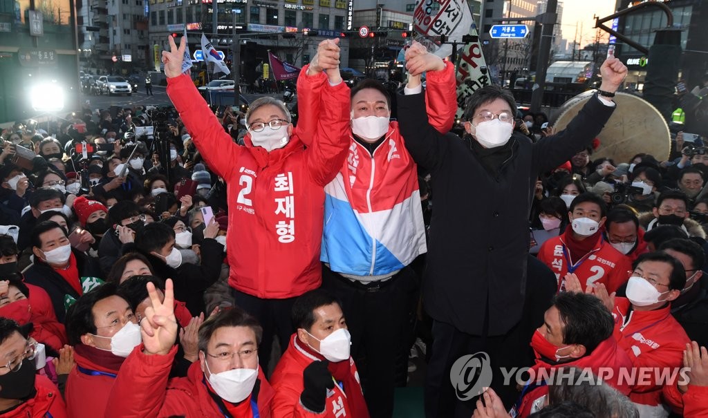 Yoon Suk-yeol (C), the presidential candidate of the main opposition People Power Party, raises his hands with his party primary rivals, Choi Jae-hyung (L) and Ryu Seung-min, during a campaign rally in central Seoul on Feb. 17, 2022. (Pool photo) (Yonhap)